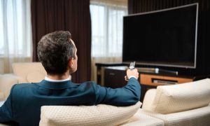 Uomo guarda la televisione seduto sul divano
